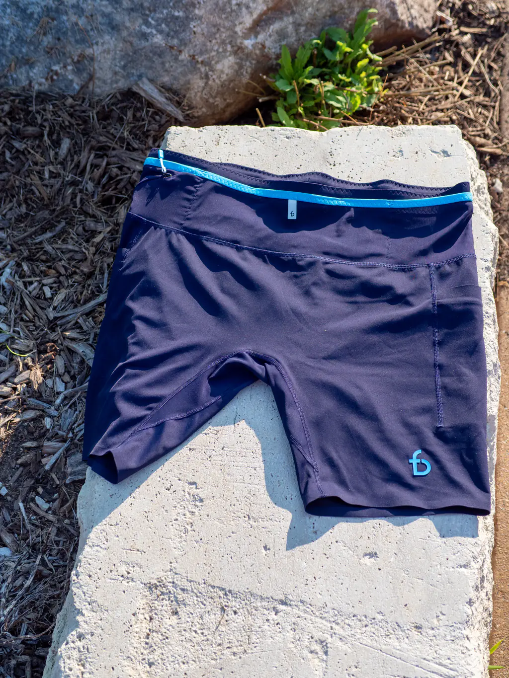 A top down, overall view of the front of the half tights, showing the contrasting blue waistband trim and logo