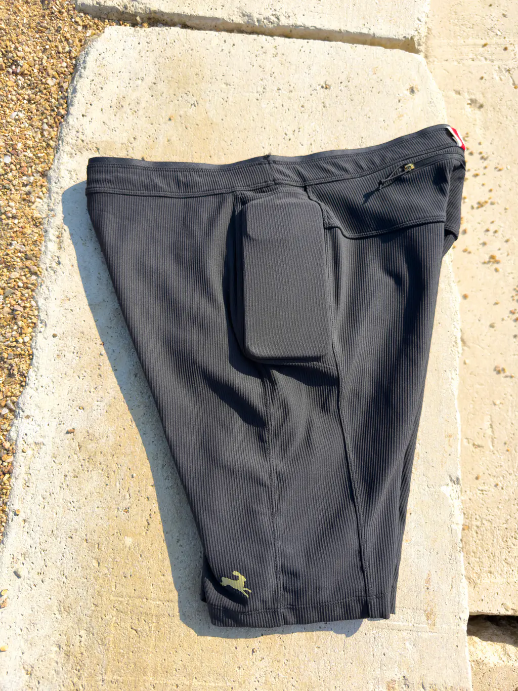 A side view of the half tights with an iPhone 12 Pro Max case in the drop-in side pocket, showing a tight fit.