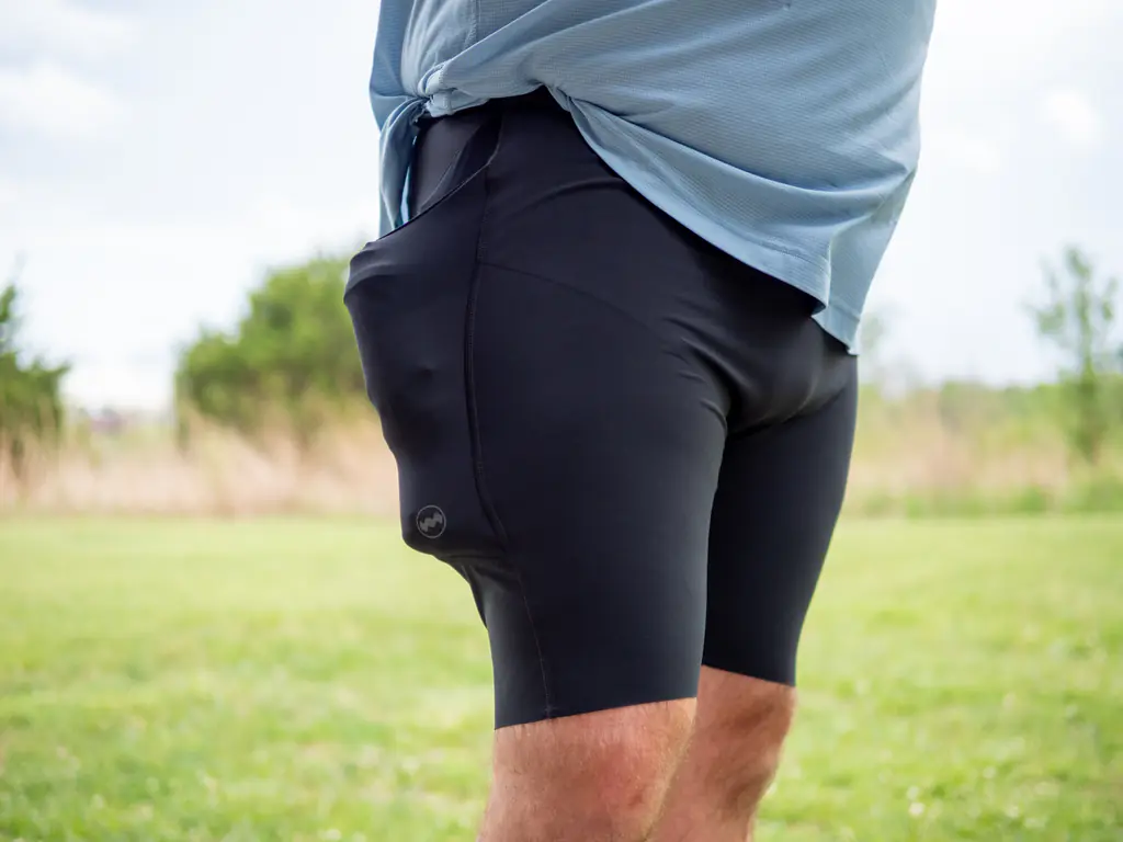 A front-side-view of a runner wearing the half tights, with the side pockets loaded with both a 500ml soft flask and a 150ml nutrition flask, which bulges quite a bit.