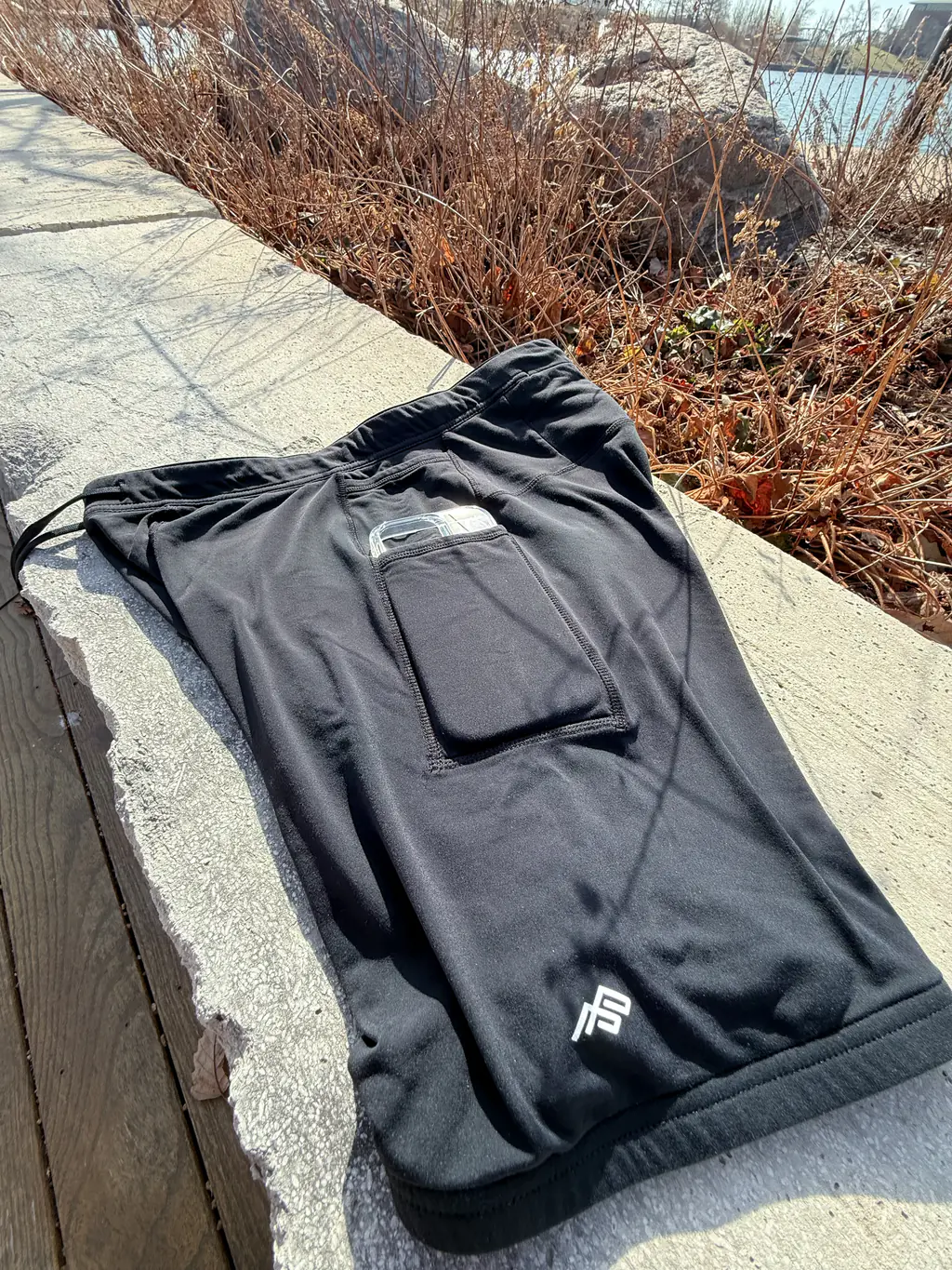 An overall side view of the half tights, showing the dual pocket system, with an iPhone 16 Pro case in the larger bottom pocket