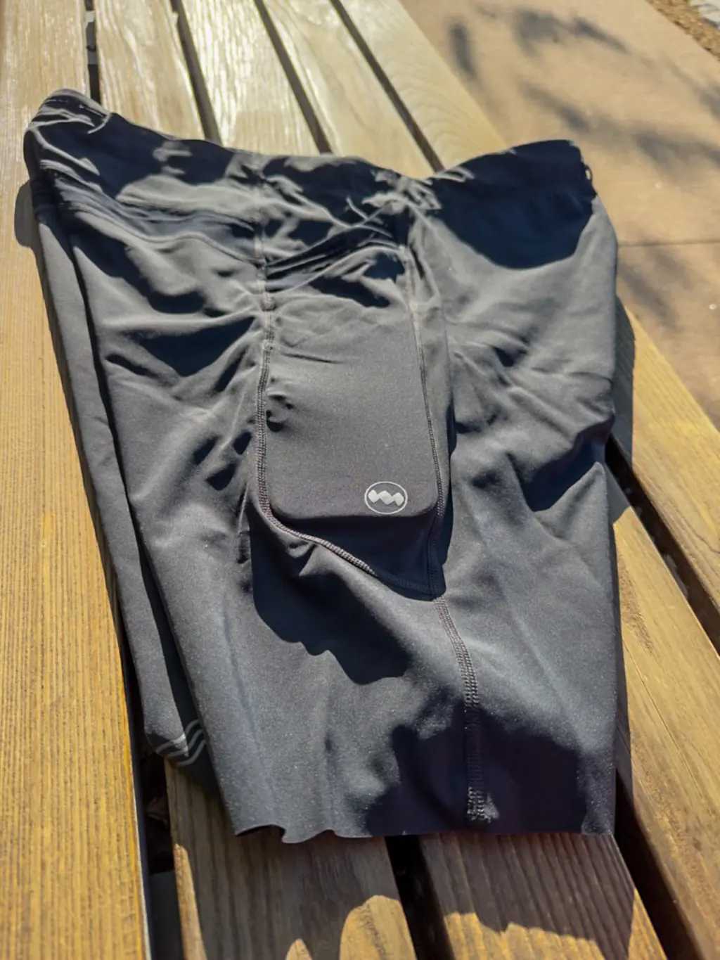 An overall side view of the half tights, showing the stacked pockets, with an iPhone Pro Max case in the rear side pocket