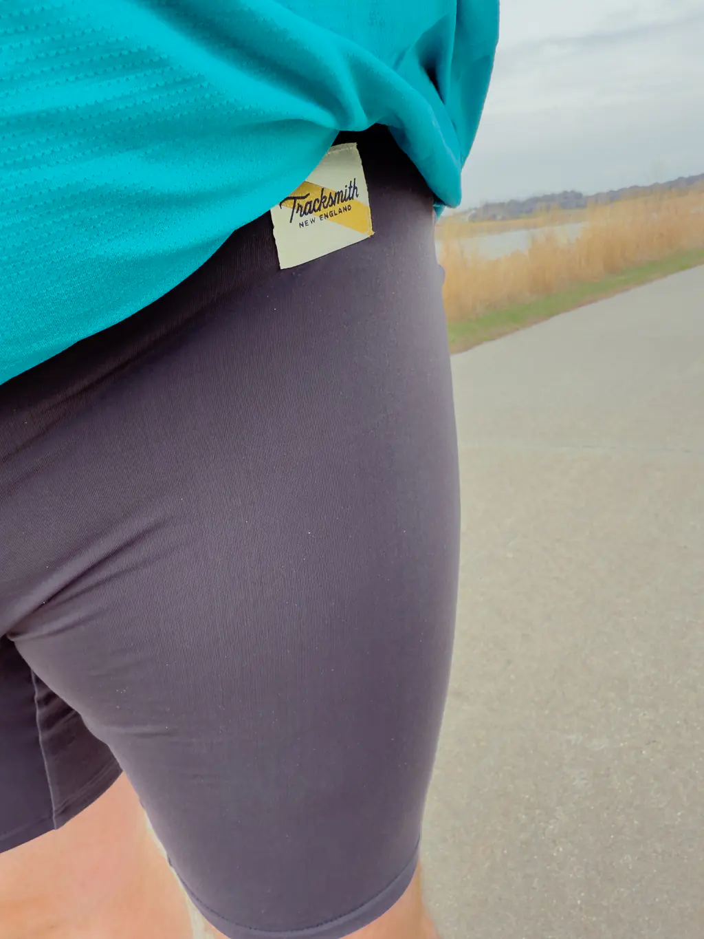 A closeup of the Tracksmith tag, while a runner is wearing the half tights