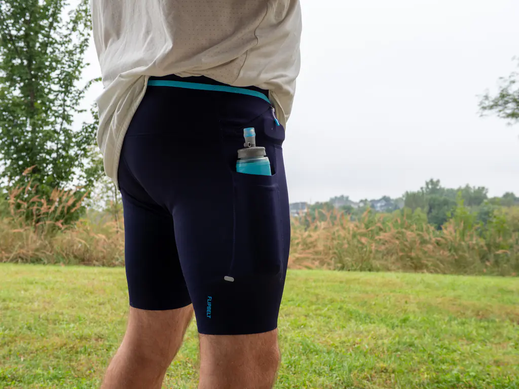 A side view of a runner wearing the half tights, with a 500ml soft flask held snugly in the thigh pocket